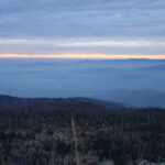 Schmaler Sonnenuntergangsstreifen zwischen Wolke und Nebel